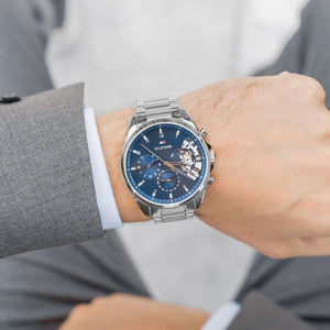 Tommy Hilfiger Baker 1710448 herrklocka med silverfärgat stålarmband och blå urtavla, visad framifrån.